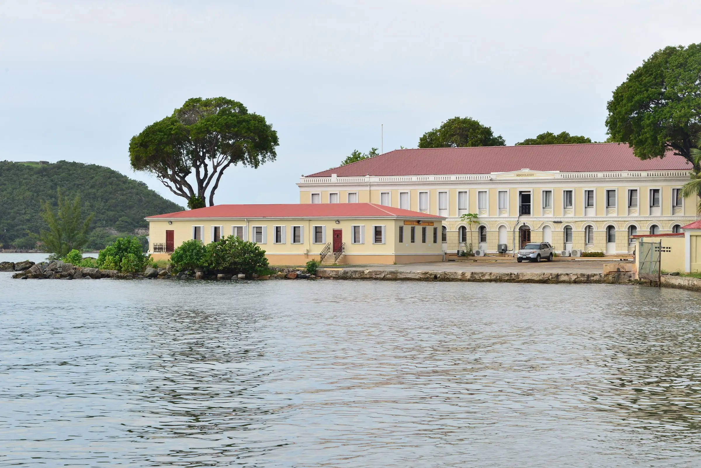 Pale yellow, red-roofed Legislature Building of the Virgin Islands on the Charlotte Amalie waterfront, seen across the harbor water