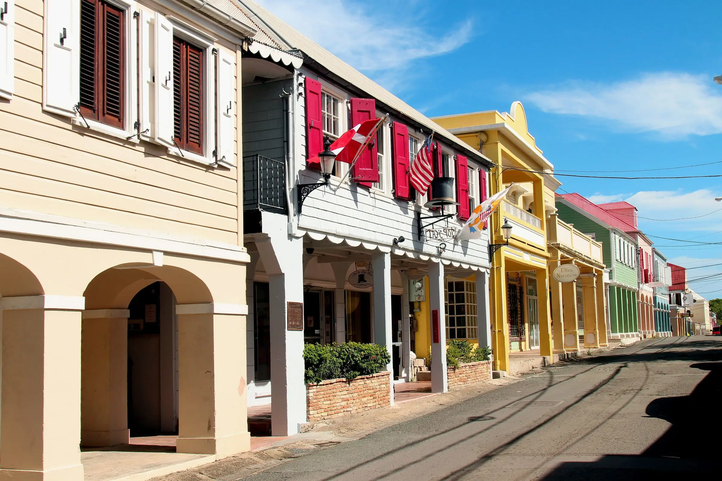 Arched sidewalk galleries along a street of colorful historic buildings in Christiansted