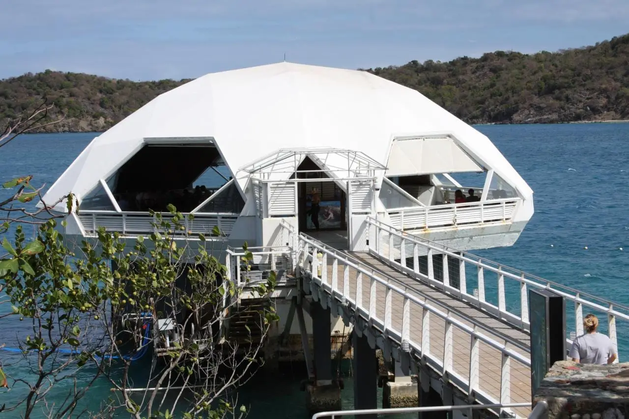 Railed footbridge leading out over blue water to the white domed Undersea Observatory Tower at Coral World Ocean Park