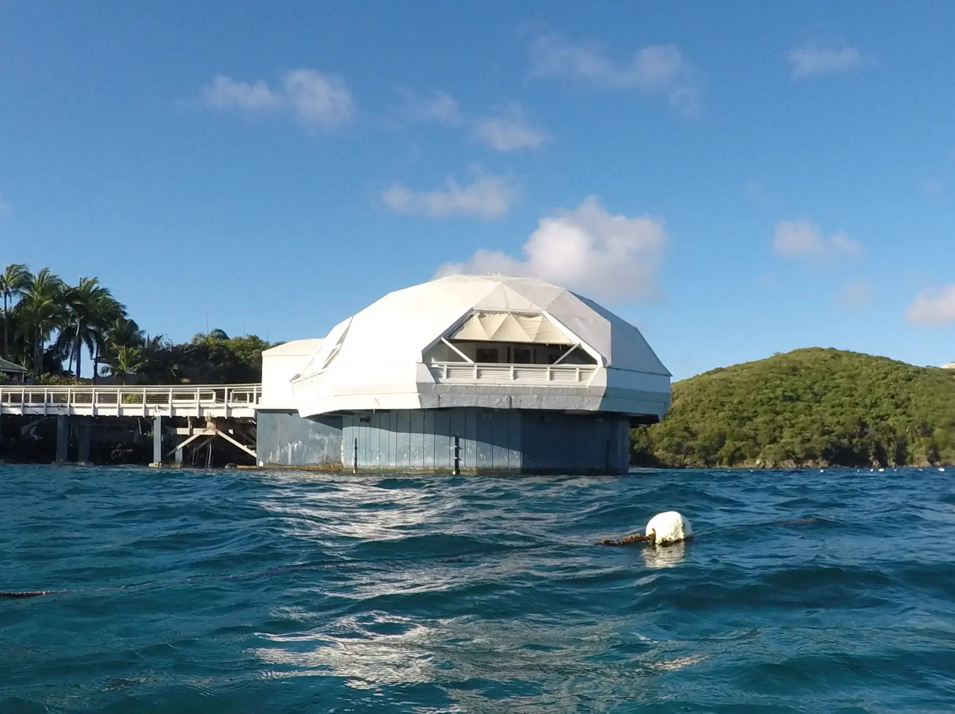 White geodesic dome of Coral World's Undersea Observatory Tower standing in the sea off Coki Point, joined to the shore by a footbridge