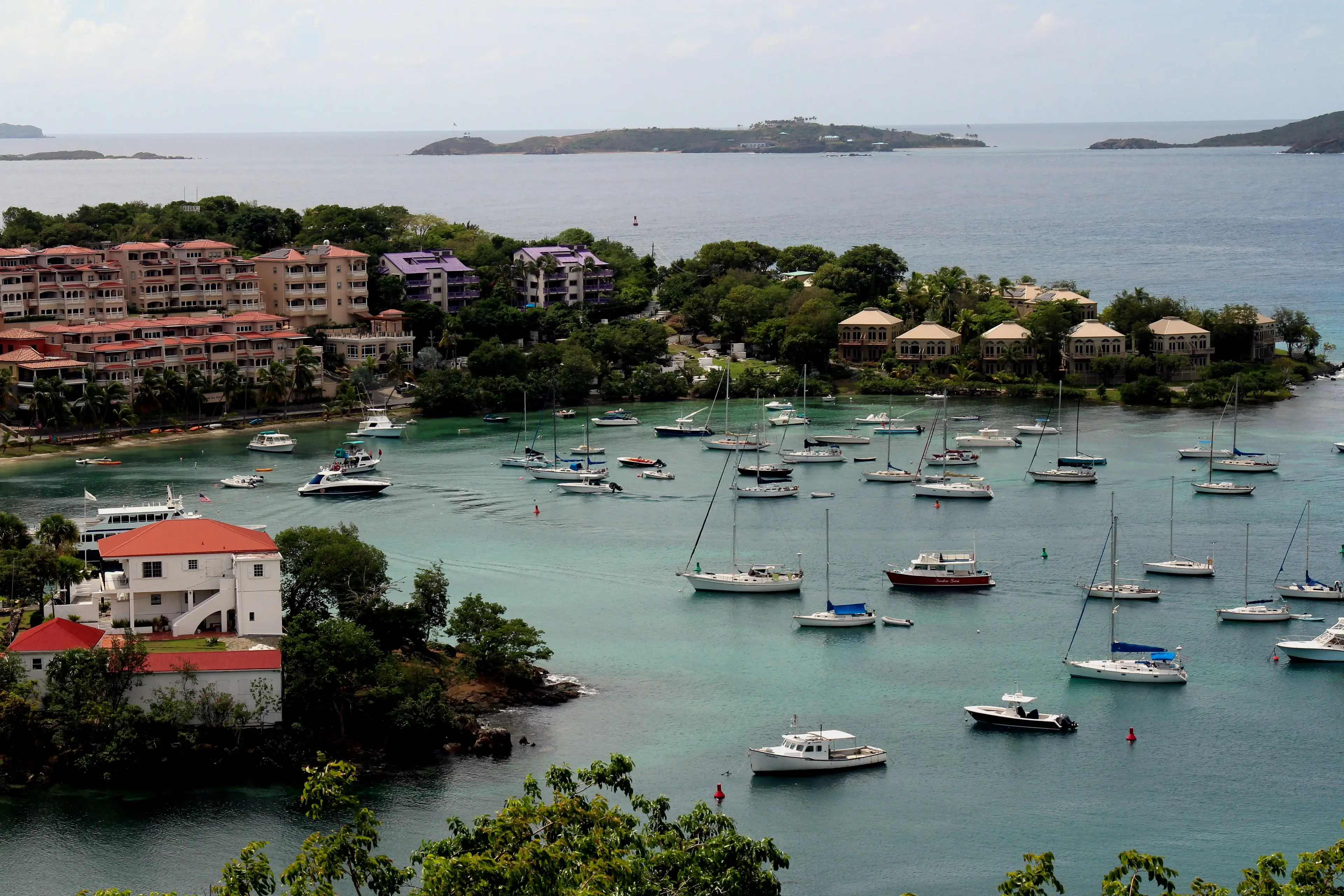 Sailboats moored in Cruz Bay below red-roofed buildings on the hillside of St. John