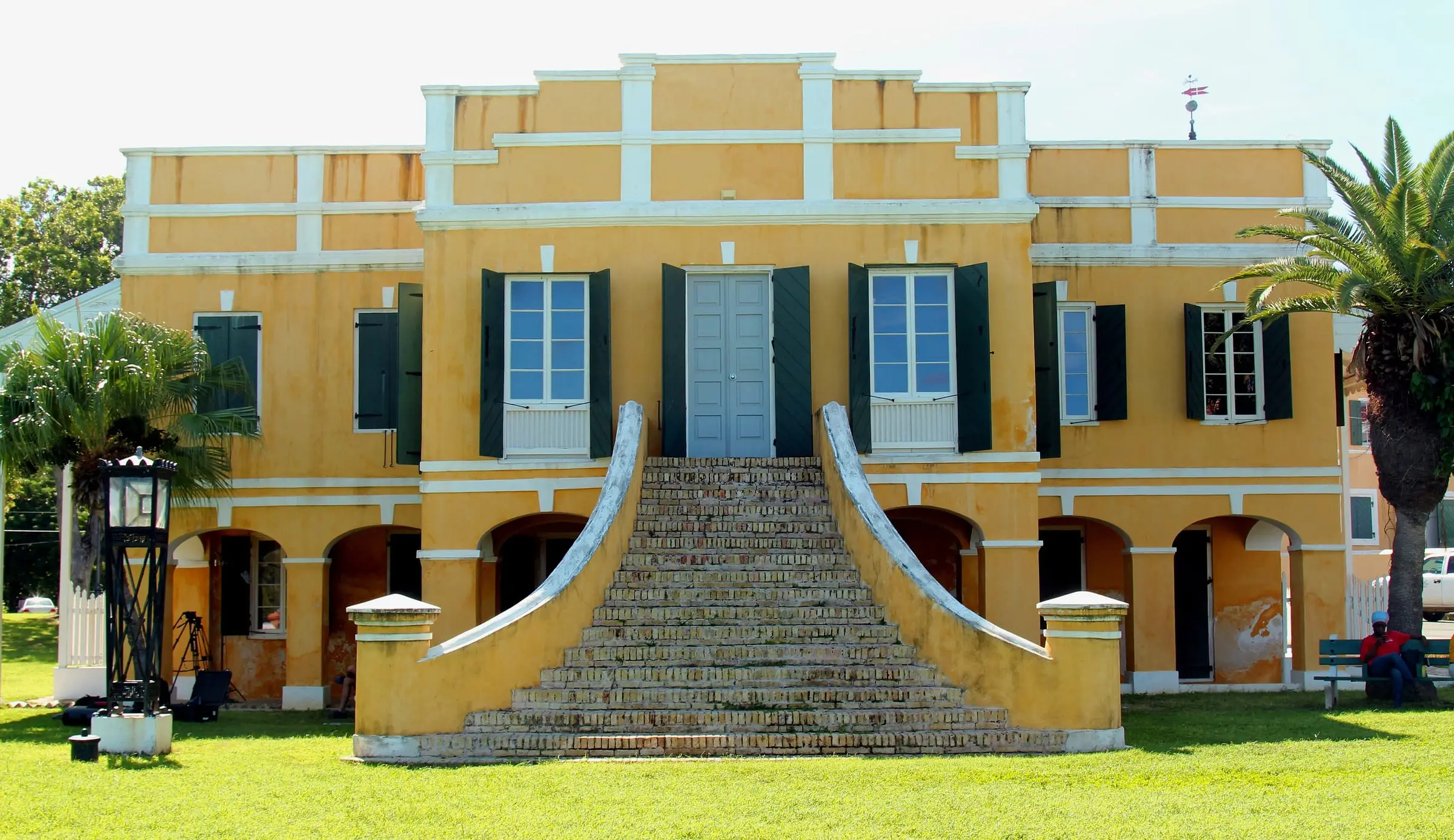 The yellow Danish Custom House in Christiansted, with dark green shutters and a flared brick staircase rising to its upper-floor doors