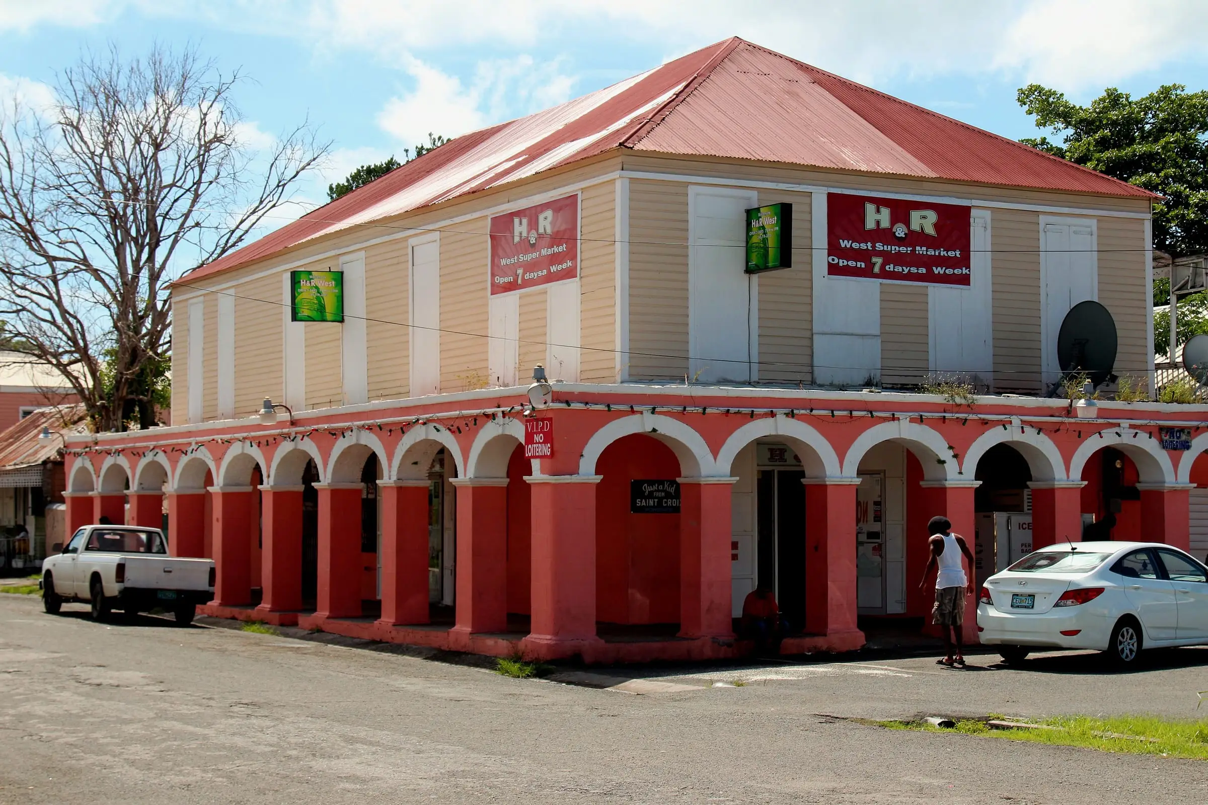 A red-roofed historic building with an arched ground-floor arcade in Frederiksted