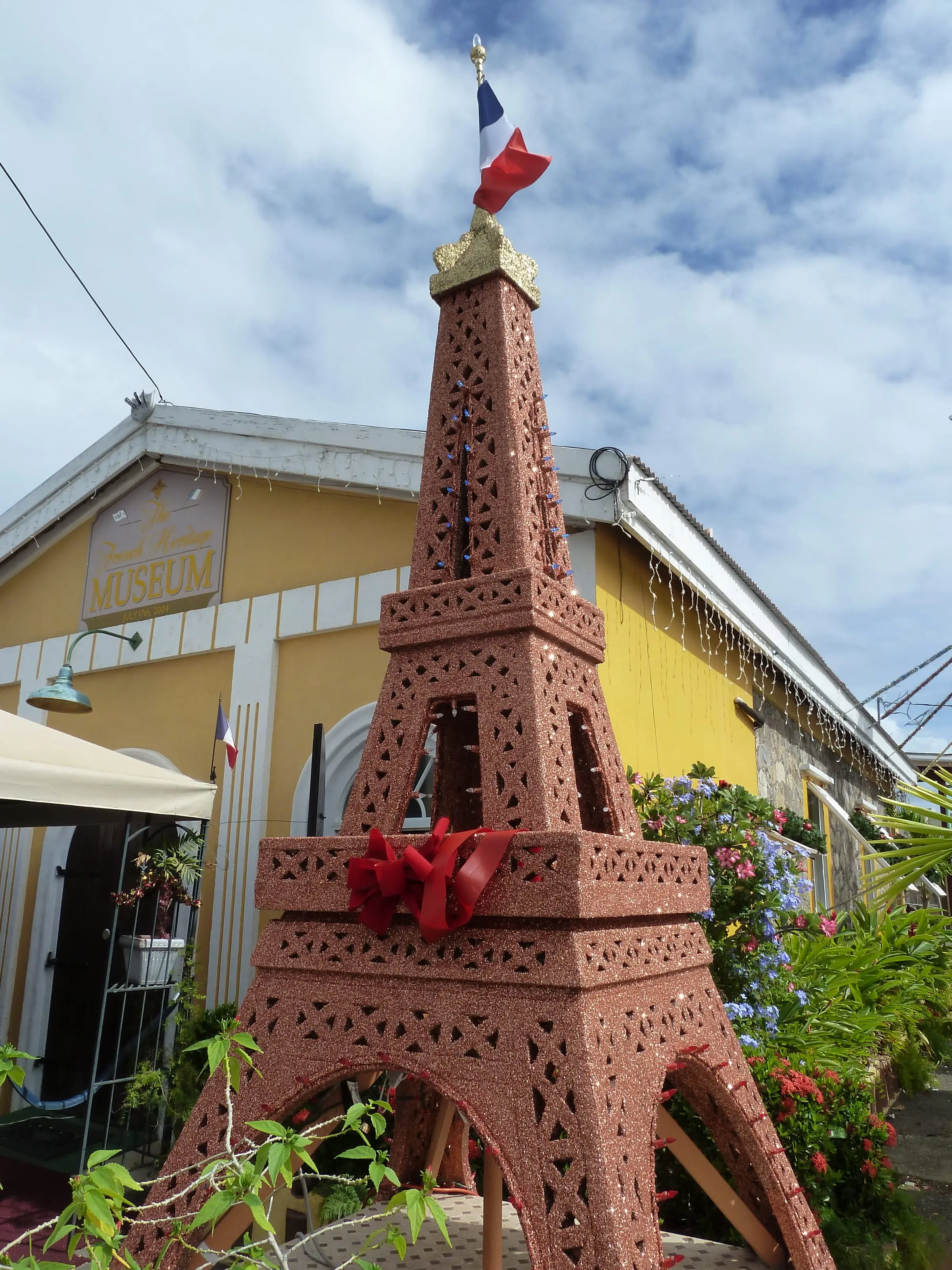 A glittering model of the Eiffel Tower with a French flag in front of the yellow French Heritage Museum in Frenchtown