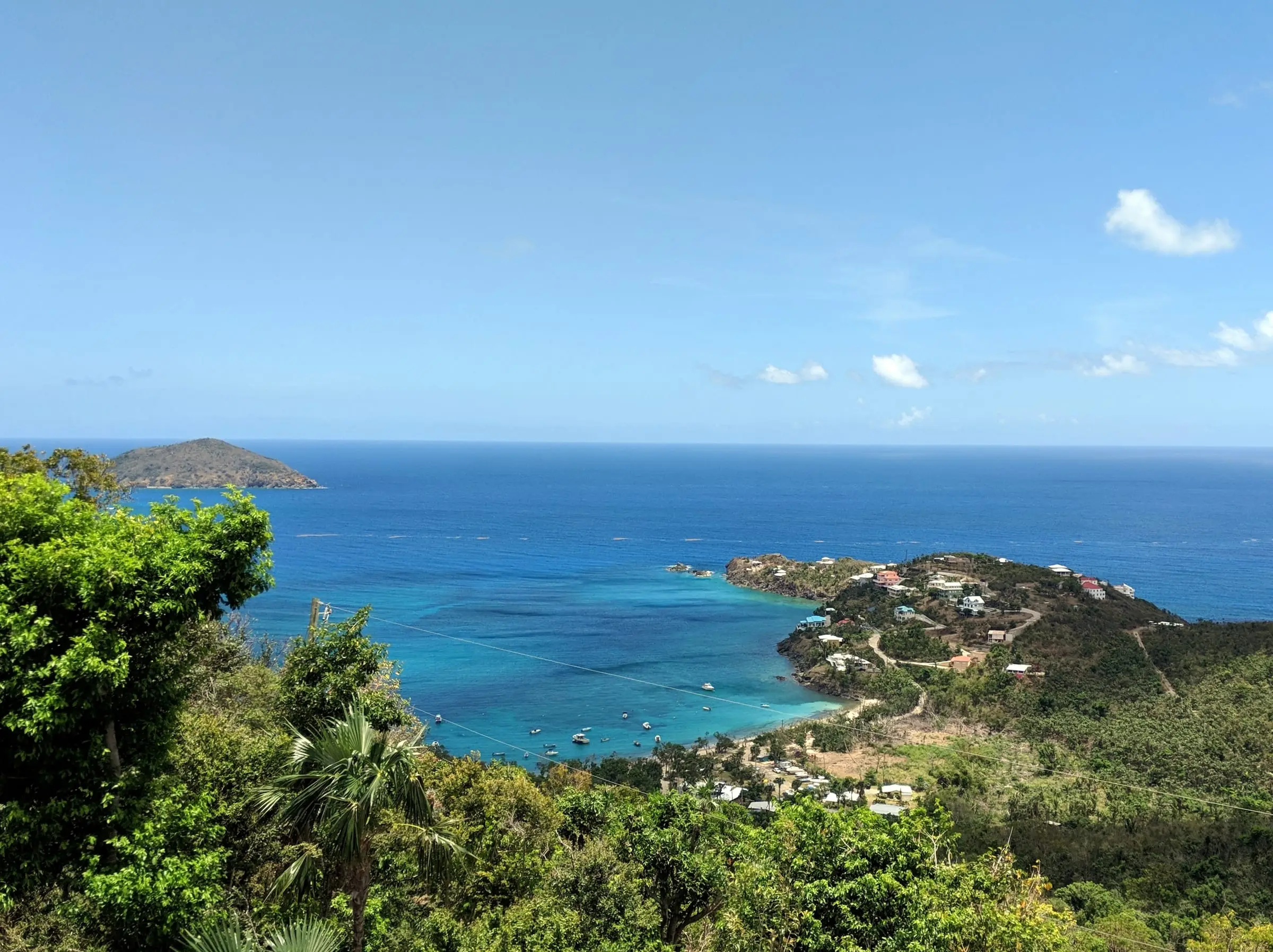 Hull Bay on the north side of St. Thomas seen from the hills, with boats in the turquoise bay, homes on a point and an island offshore