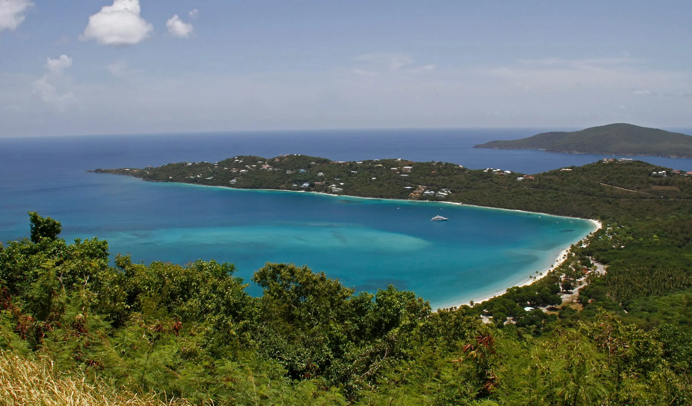 The curved white-sand beach and turquoise water of Magens Bay seen from the hills of St. Thomas