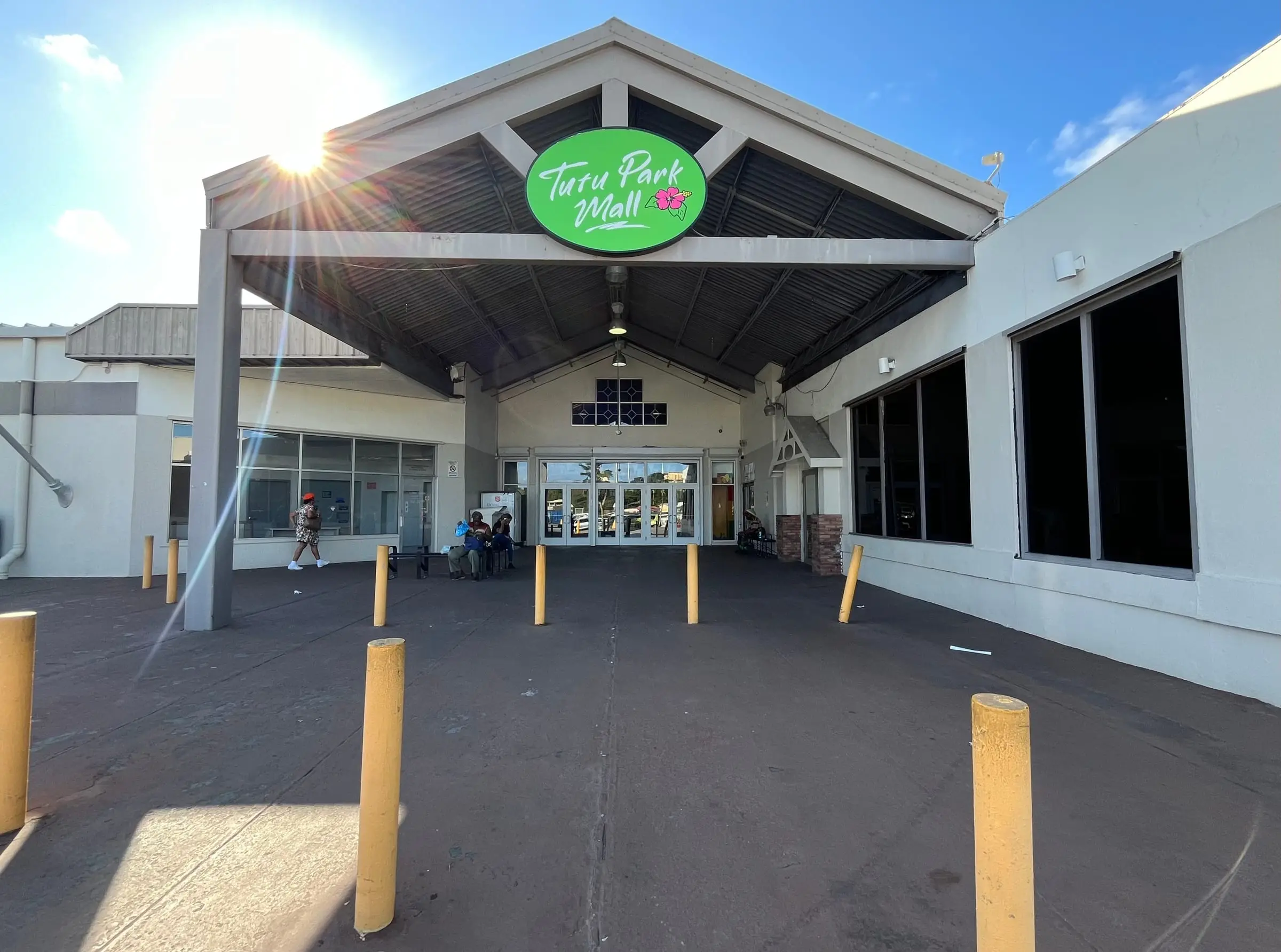 The covered entrance of Tutu Park Mall on St. Thomas, with its green sign and yellow bollards