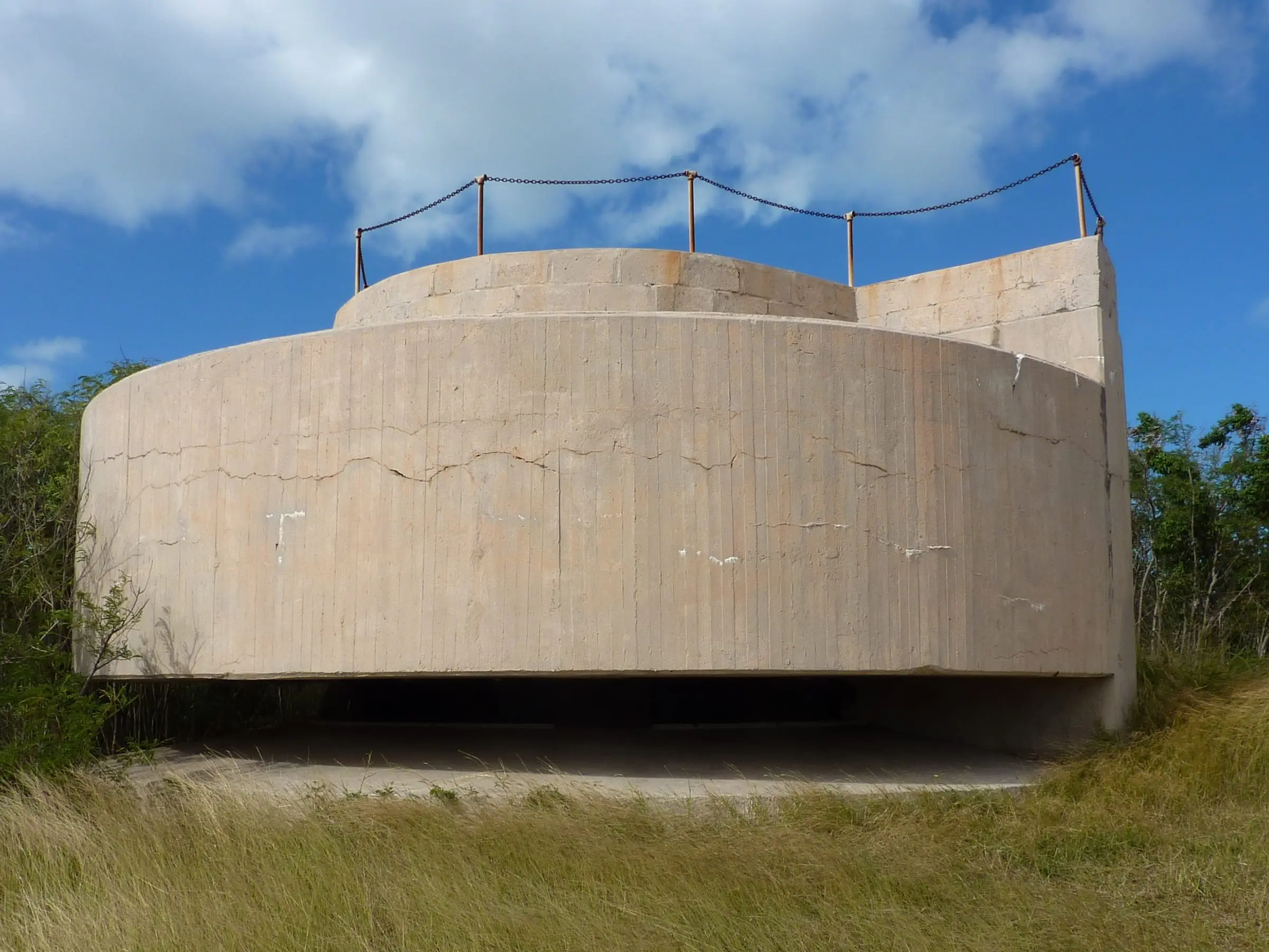 A curved concrete World War II gun emplacement at Fort Segarra on Water Island, surrounded by grass and scrub